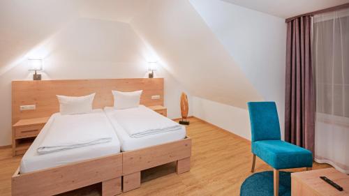 a bedroom with a bed and a blue chair at Hotel - Stadtvilla Central in Schweinfurt