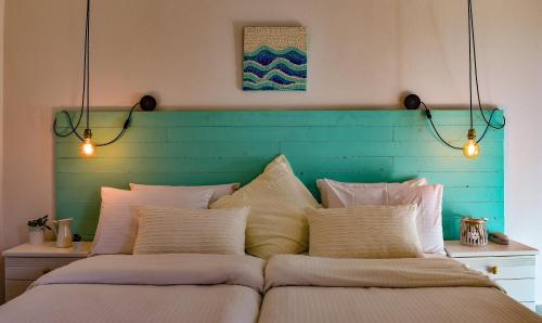 a bed with a blue headboard with lights above it at Andriana in Agios Georgios