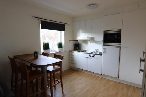 una cucina con armadi bianchi e tavolo con sedie di Studio Apartment a Karlshamn