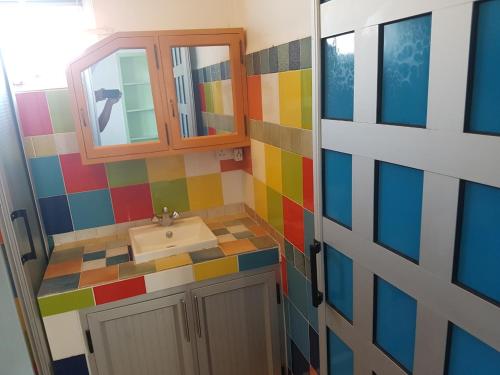 La salle de bains colorée est pourvue d'un lavabo et d'un miroir. dans l'établissement Lapiroguevilla[Tourist resident], à Pereybere