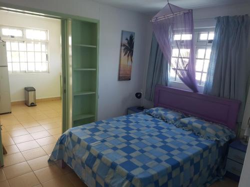 a bedroom with a blue bed in a room with windows at Lapiroguevilla[Tourist resident] in Pereybere