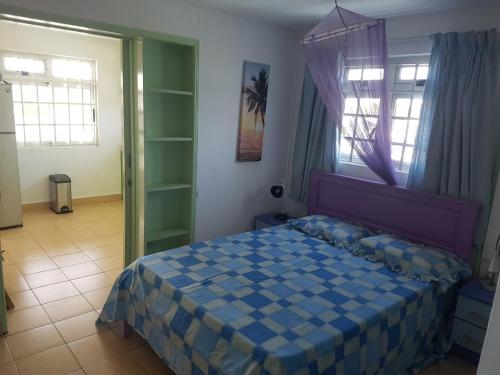 - une chambre avec un lit bleu dans une pièce dotée de fenêtres dans l'établissement Lapiroguevilla[Tourist resident], à Pereybere