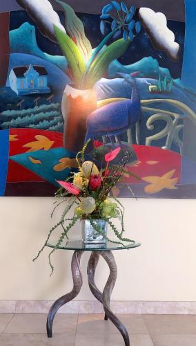 a vase of flowers on a glass table in front of a painting at Atlanticview Cape Town Boutique Hotel in Cape Town