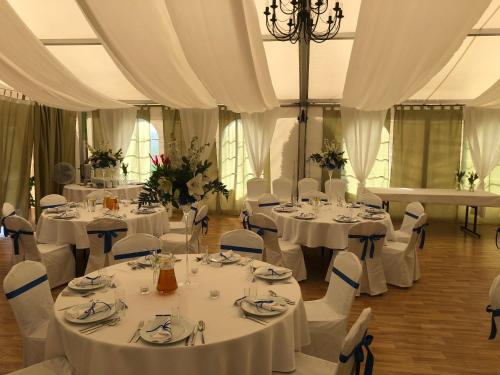 a room with white tables and chairs with white curtains at RJ Hotel in Pabianice
