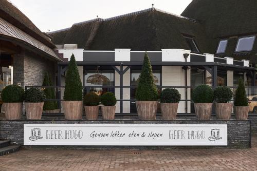 a sign in front of a house with potted plants at Hotel Heer Hugo in Heerhugowaard