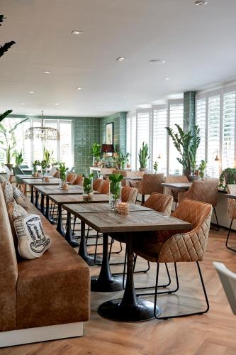 a dining room with tables and chairs and windows at Hotel Heer Hugo in Heerhugowaard