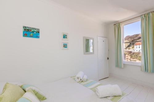 een witte kamer met een bank en een raam bij Ravenscraig House in Staithes