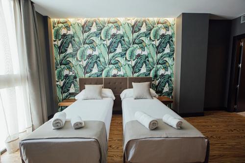 two beds in a room with a mural on the wall at Málaga Premium Hotel in Málaga