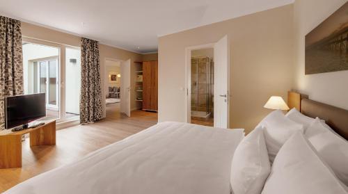 a bedroom with a white bed and a television at Hotel Villa Toskana in Leimen
