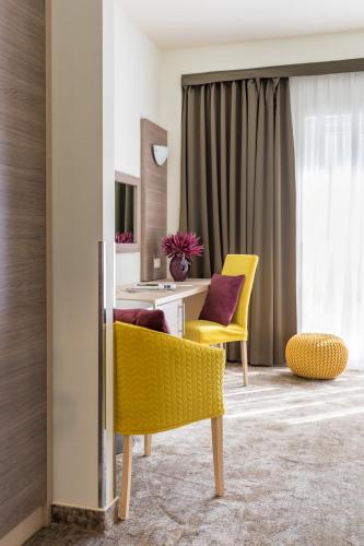 a living room with yellow chairs and a table at Hotel Mondo in Split