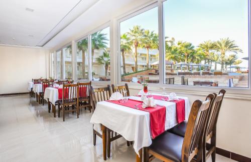 una sala da pranzo con tavoli, sedie e finestre di Empire Beach Aqua Park a Hurghada