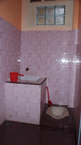 a pink tiled bathroom with a toilet and a sink at TriDwi Homestay in Parakan