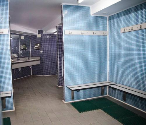 baño con paredes de azulejos azules y banco en Albergue Municipal San Cipriano, en Ayegui