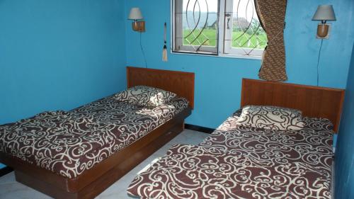 a bedroom with two beds and a blue wall at TriDwi Homestay in Parakan