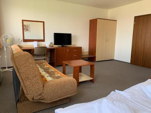a hotel room with a couch and a desk and a tv at Hotel Patriot in Vranov nad Topľou