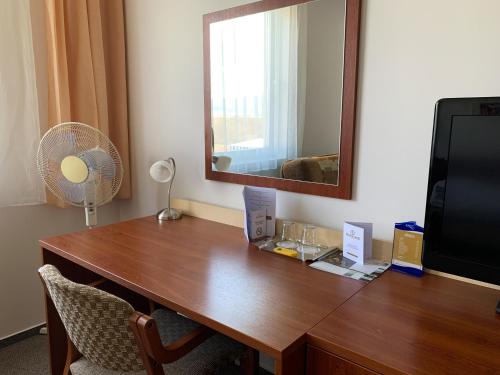 a wooden desk with a mirror and a television at Hotel Patriot in Vranov nad Topľou