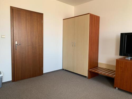a room with a wooden cabinet and a television at Hotel Patriot in Vranov nad Topľou