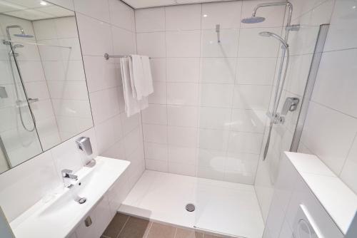 een witte badkamer met een douche en een wastafel bij Amrâth Hotel Lapershoek Arenapark in Hilversum