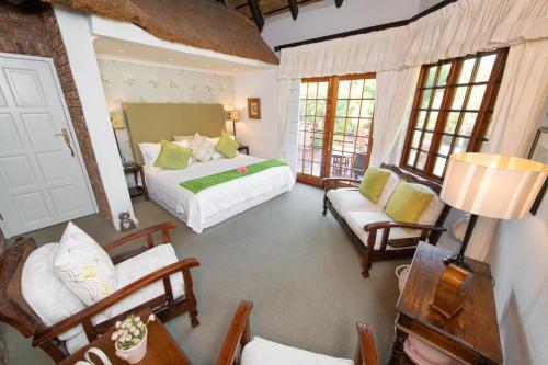 a bedroom with a bed and a couch and chairs at Blyde River Canyon Lodge in Hoedspruit