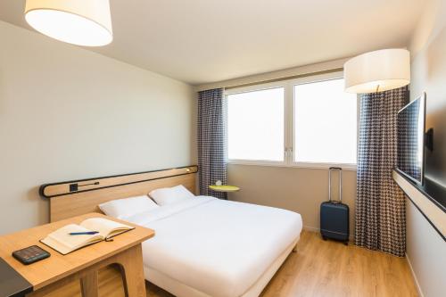 a hotel room with a bed and a desk and window at Aparthotel Adagio access Palaiseau Saclay in Palaiseau