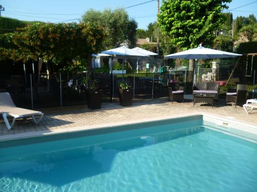 a swimming pool with chairs and umbrellas in a yard at Hotel Cayrons Vence & St Paul de Vence in Vence