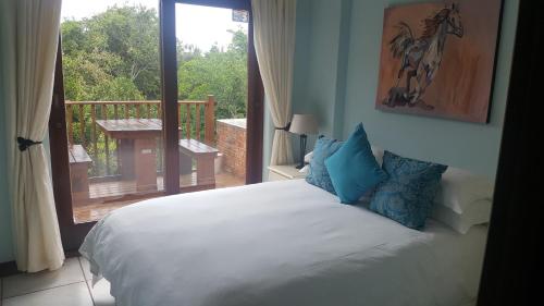 Schlafzimmer mit einem Bett und Blick auf einen Balkon in der Unterkunft Lent@Grootbrak in Groot Brak Rivier