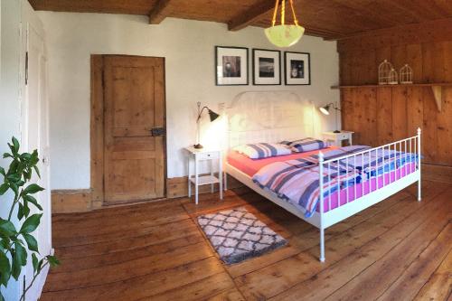 Schlafzimmer mit einem Bett, einem Tisch und einer Tür in der Unterkunft La Cachotière in La Chaux-du-Milieu