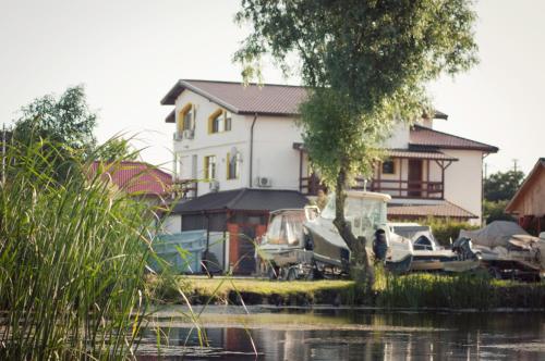 a house with boats parked in front of it at Pensiunea Califar in Dunavăţu de Jos