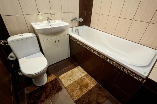 a bathroom with a toilet and a sink and a tub at Babylon Apartments on Vidinska in Rivne