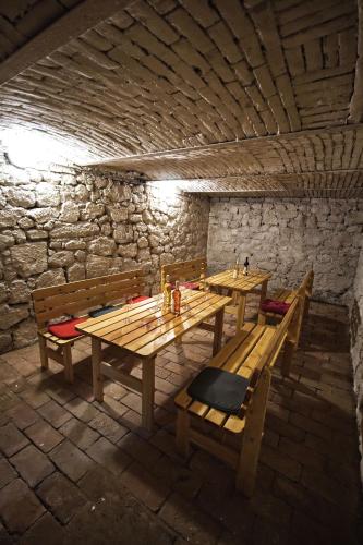 two wooden tables and benches in a stone room at "U Čápa" Krásný apartmán v Sedleci in Sedlec