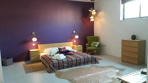 a bedroom with a bed and a green chair at Sliema La Loggia Suites in Sliema
