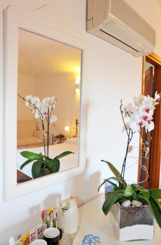 a mirror on a wall above a counter with flowers at Hotel Il Piccolo Golf in Porto Cervo