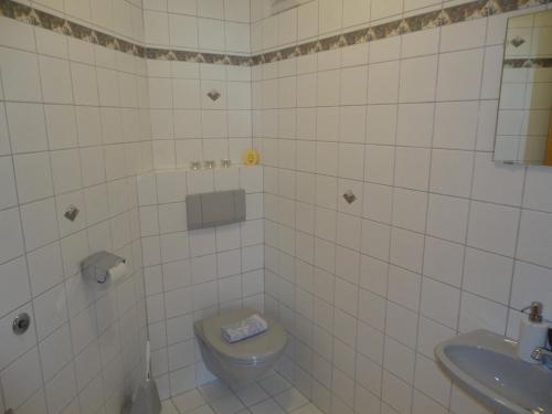 アプテナウにあるFerienwohnung Ronacherの白いタイル張りのバスルーム(トイレ、シンク付)