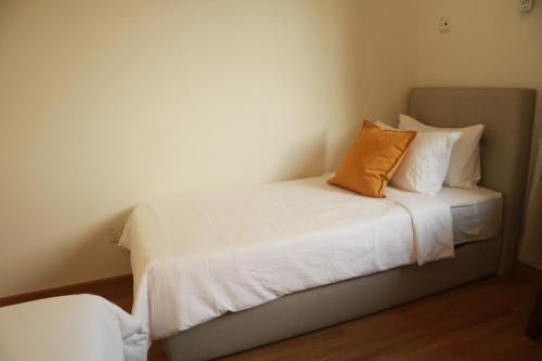 a bed with white sheets and an orange pillow at IKO homes in Kota Kinabalu