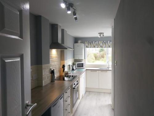 una cucina con armadi bianchi e piano di lavoro di Wyken House - 3 Bedroom House Coventry- Sleeps 5 - Rated Superb a Coventry