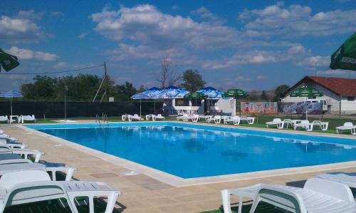 a large swimming pool with white chairs and umbrellas at Drumul Dragostei in Vintu De Jos