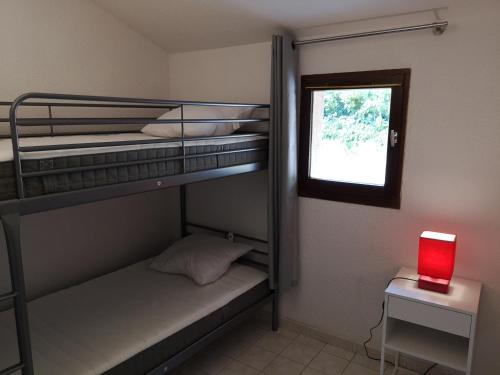 Cette chambre comprend 2 lits superposés et une fenêtre. dans l'établissement Résidence Cap Azur Maison N° 31, à Villeneuve-Loubet