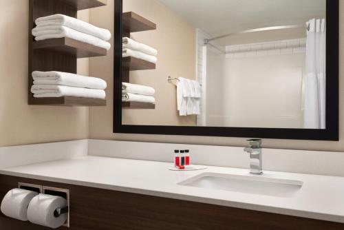 a bathroom with a sink and a mirror at Ramada by Wyndham Airdrie Hotel & Suites in Airdrie