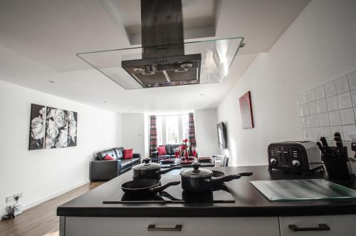 a kitchen with a stove with pots and pans on it at Orange Apartments Polmuir Gardens Only 7 minutes to City Centre in Aberdeen
