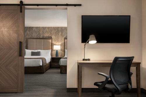 a hotel room with a bed and a desk and a chair at Canalta Airdrie in Airdrie
