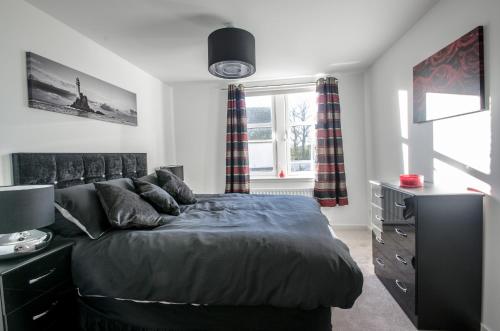 - une chambre avec un lit, une commode et une fenêtre dans l'établissement Orange Apartments Polmuir Gardens Only 7 minutes to City Centre, à Aberdeen