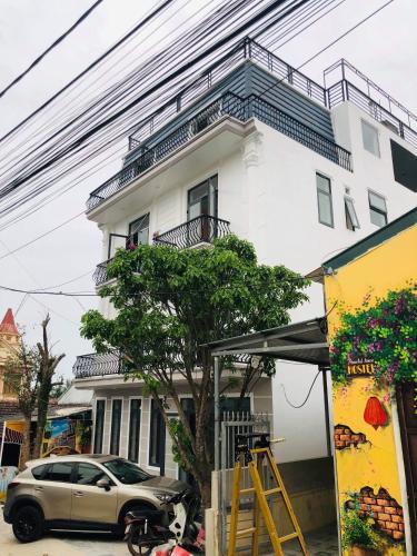 a car parked in front of a white building at Peaceful House Hostel in Dong Hoi