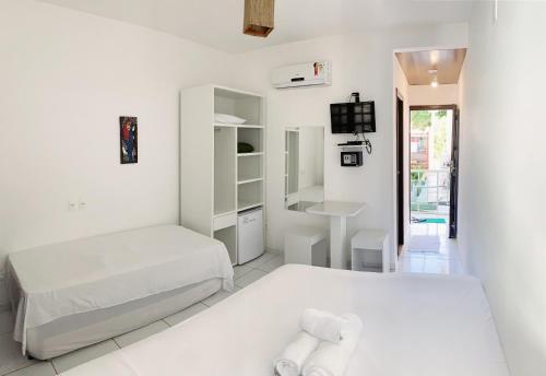 Habitación blanca con 2 camas y TV. en Pousada Brasil Caribe, en Morro de São Paulo