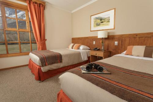 Habitación de hotel con 2 camas y ventana en Hotel Las Torres Patagonia, en Torres del Paine