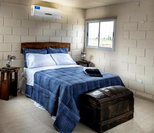 a bedroom with a bed with a blue blanket and a window at Finca Las Pircas Casa de Adobe in Famatina