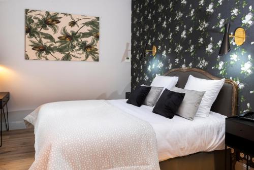 a bedroom with a white bed with a floral wallpaper at Hotel Clos Castel Villas Spa in Casteljaloux