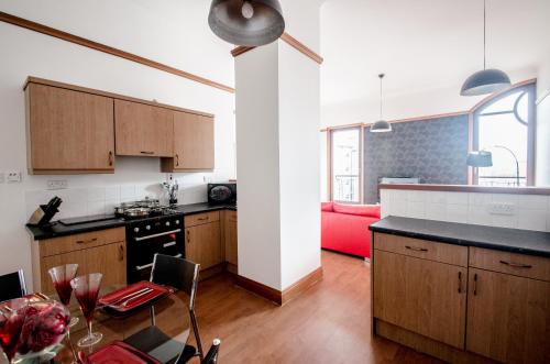 uma cozinha com armários de madeira e um sofá vermelho em City Centre Orange Apartments Bastille em Aberdeen