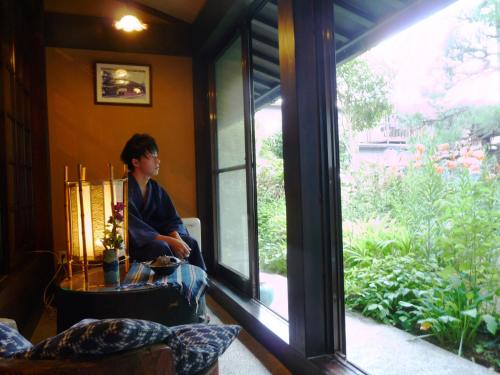 a boy sitting in a room looking out a window at Ryokan Asunaro in Takayama