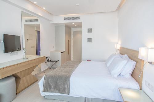 a bedroom with a bed and a desk and a television at Kokkinos Boutique Hotel in Protaras