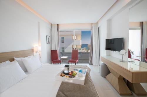 a hotel room with a bed and a table with food on it at Kokkinos Boutique Hotel in Protaras